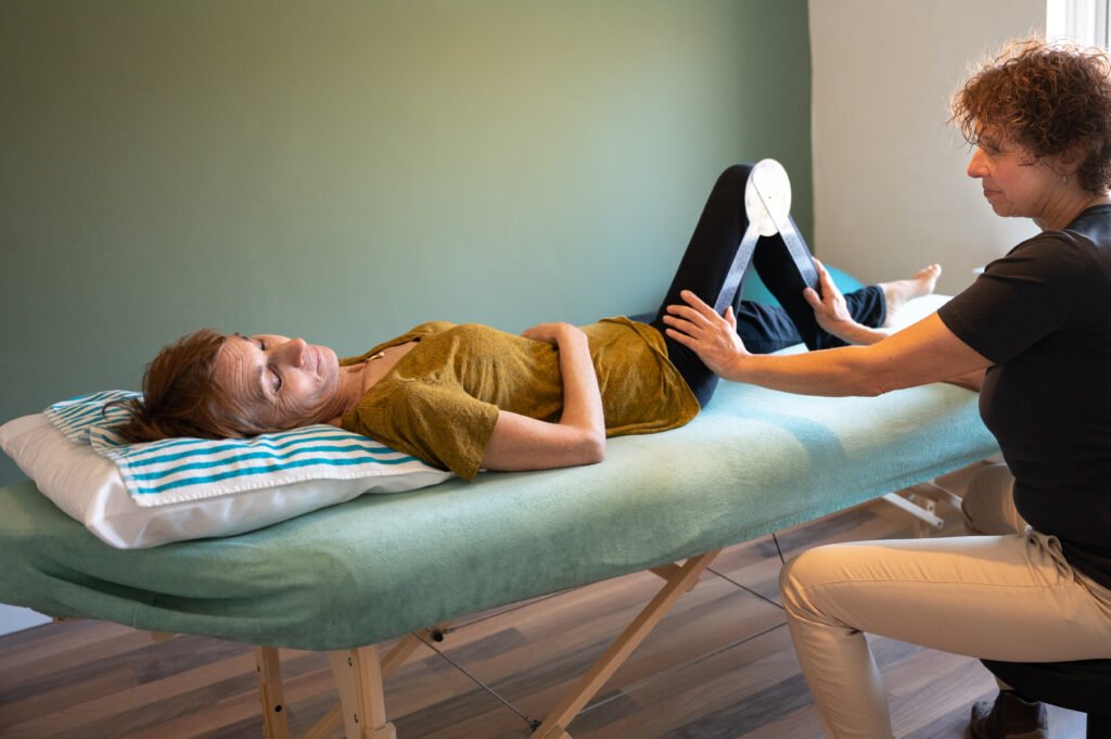 Fysiotherapeut meet ROM van been patiente op behandeltafel